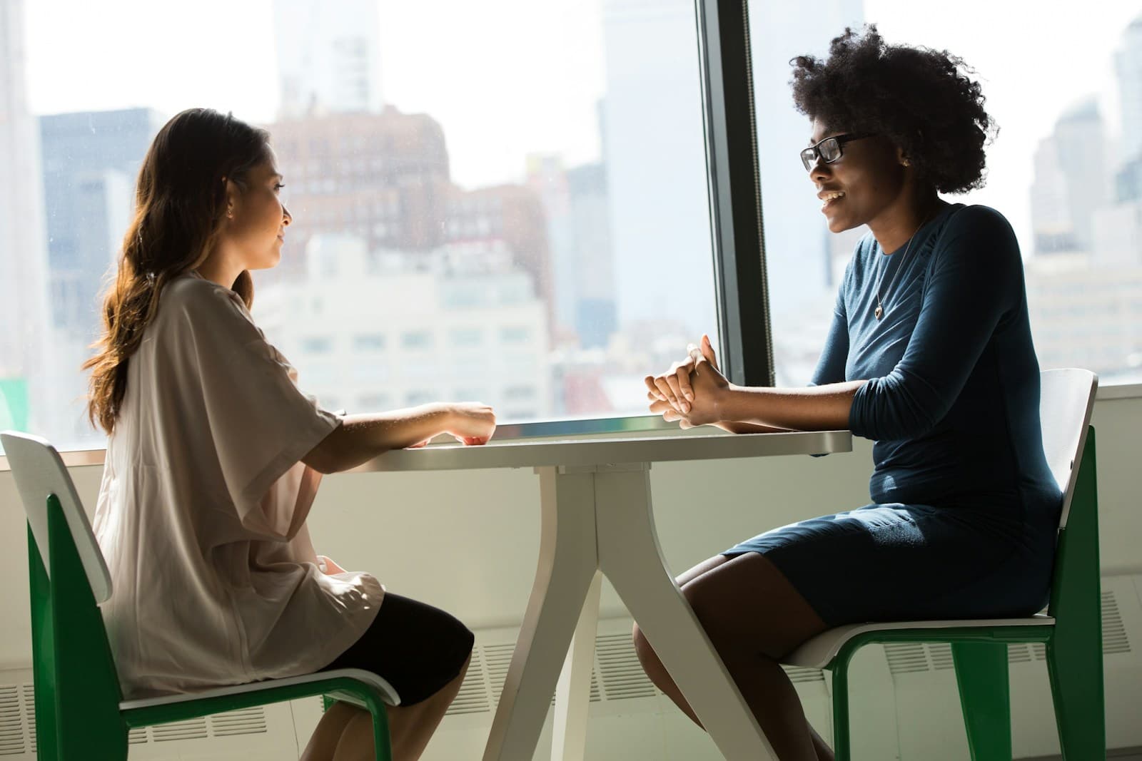Two professionals in a focused conversation beside a window